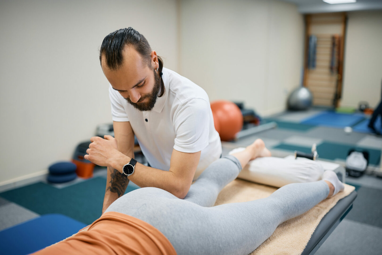 Professional physiotherapist massaging leg of a sportswoman at health club.